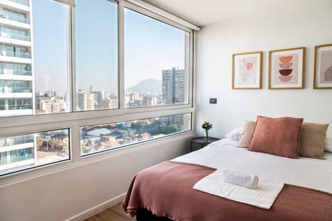 Enjoy breathtaking city views from this modern, cozy bedroom with stylish decor and plush bedding.