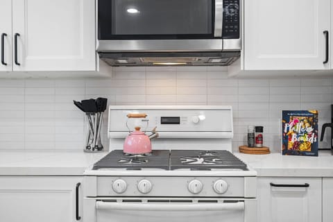 A contemporary kitchen, focusing on a clean white cooking area.
