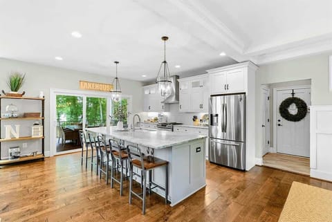 A spacious and modern kitchen with a large marble island, high-end appliances, elegant pendant lighting, and open access to the dining and living areas with views of the backyard.