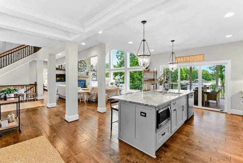 A spacious and modern kitchen with a large marble island, high-end appliances, elegant pendant lighting, and open access to the dining and living areas with views of the backyard.
