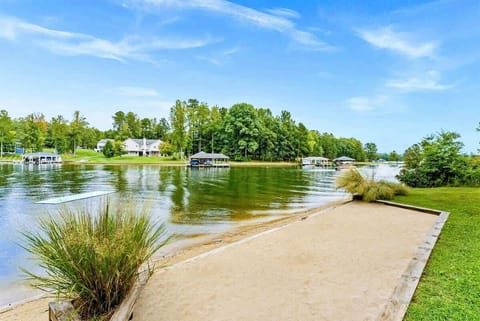 A private sandy beach area with a peaceful view of the lake, surrounded by lush greenery and nearby boat docks.