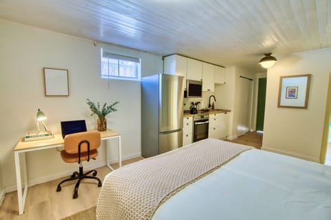 Bright and welcoming space featuring a comfy bed, functional workspace, and modern kitchenette—everything you need in one view.