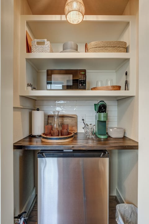 Kitchenette with mini fridge, coffee maker, glassware, flatware, and microwave