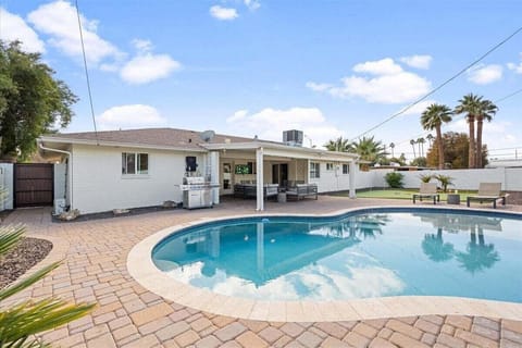 Private Backyard featuring a sparkling pool, Grill, private patio with a smart TV and outdoor seating, sun loungers, and mini golf.