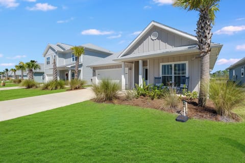 Modern coastal home with tropical landscaping and palm trees in a well-maintained residential neighborhood.