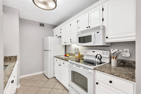 To your left from the entrance, a fully-equipped galley-style kitchen awaits, simplifying meal preparation.