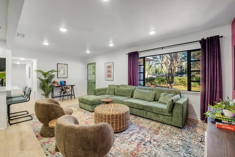 Living room with plush couch, dedicated workspace and windows with curtains