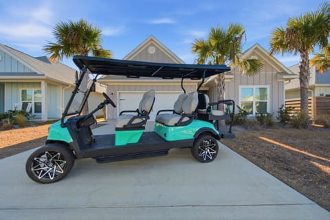 Modern beach home with tropical landscaping and convenient golf cart for exploring the area.