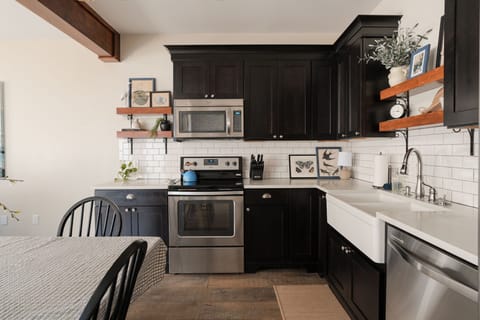 Fully stocked kitchen with an electric stove, garbage disposal, and cookware