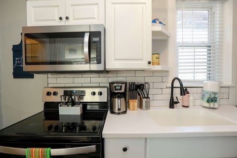 Kitchen with stove, oven, coffee maker, utensils, storage space, micrwave, a window and soap. 