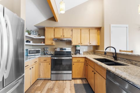Full kitchen with stainless steel appliances and breakfast bar seating.