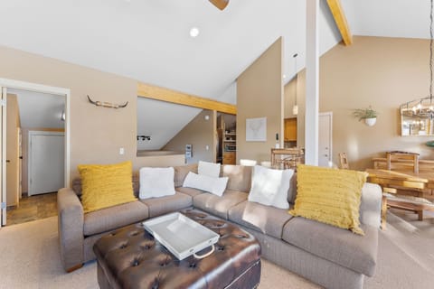 Living area with vaulted ceilings, flat-screen TV over a wood burning fireplace, double sized sleeper sofa, and balcony access.