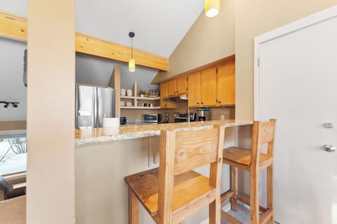 Full kitchen with stainless steel appliances and breakfast bar seating.