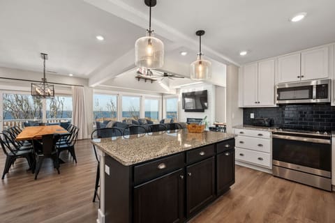 Sleek, open kitchen w/ large island, bar seating, & bright finishes designed for easy group cooking