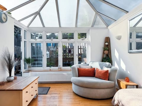 Cosy space in conservatory with heating, snuggle sofa, mini fridge and beautiful views of garden