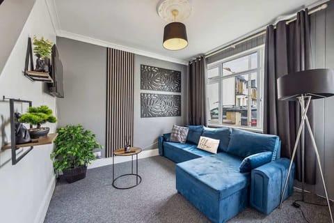 A cozy living room with comfortable sofas, green decorations, and framed artwork on the walls.
