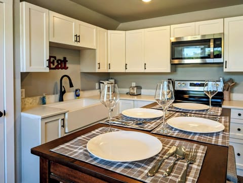 Pub-style table next to a full kitchen with new stainless steel appliances