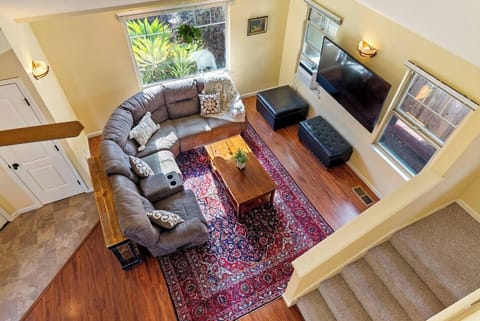 A spacious living room, featuring a large sectional sofa, a rich Persian-style rug, and a wall-mounted flat-screen television, is perfect for cozy family movie nights or relaxing in style.