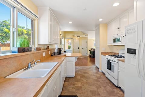 A bright galley-style kitchen, featuring crisp white cabinetry, durable stone-look countertops, and high-quality white appliances, perfect for preparing family meals or hosting intimate gatherings.