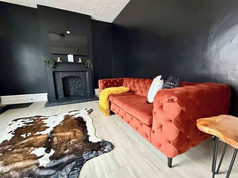 "& Unwind in style in our modern Jungle House living room in Columbus! Our vibrant orange tufted sofa, cozy yellow throw blanket, and chic cowhide rug create the perfect space to relax. & Our plants are looking forward to hosting you soon Book y