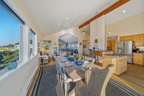 Dining table open to kitchen with breakfast bar and access to deck with ocean view
