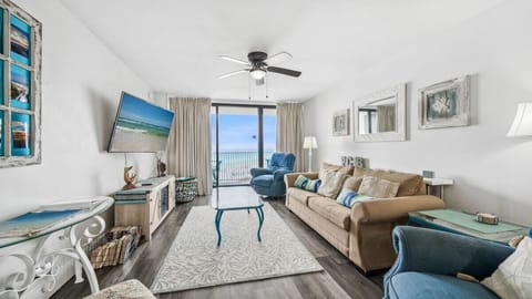 This coastal-themed living room features comfy seating, a large smart TV, and balcony access with breathtaking Gulf views. Perfect for relaxing after a day at the beach.