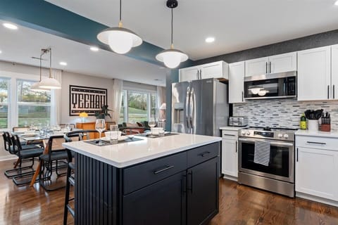 Modern kitchen with black & white cabinets, stainless appliances & large island.