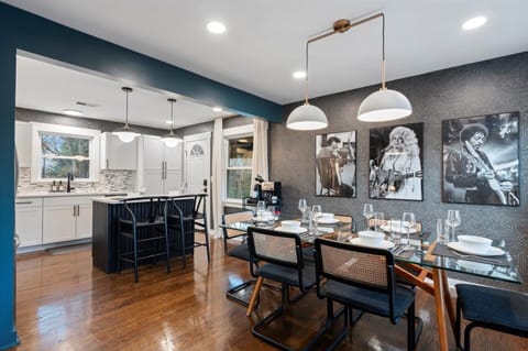 Dining area with glass table, rattan chairs & music legend gallery wall.