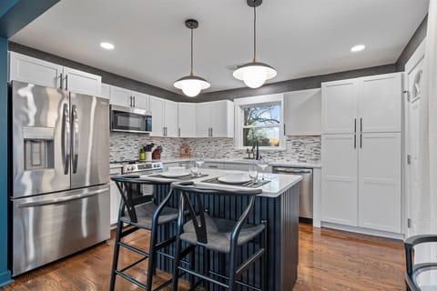 Modern kitchen with white cabinets, black island, bar seating & natural light.
