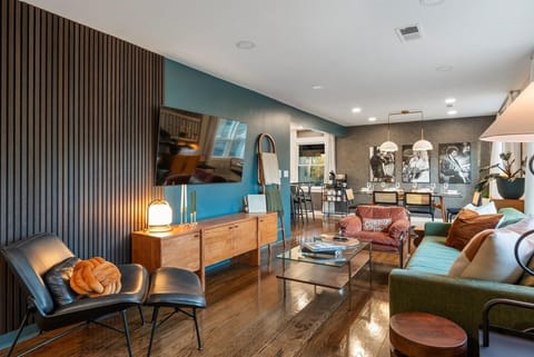 Bright living room with wood wall, green sofa, leather lounger & TV.