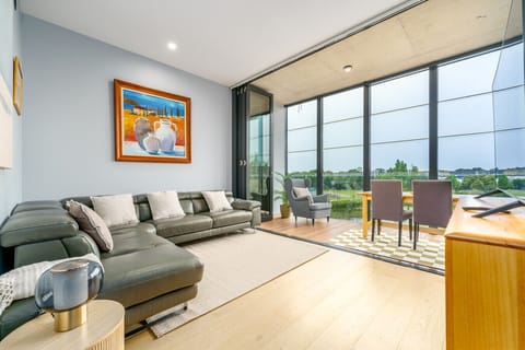 The lounge room features a luxurious leather lounge, a smart TV, and stunning views through expansive windows that flood the space with natural light.