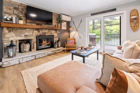 Cozy living room framed by stone fireplace & peaceful lake views