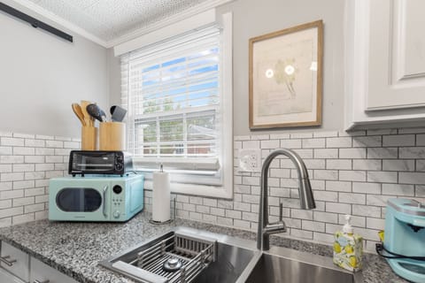 This kitchen is equipped with all the essentials, including a stylish backsplash, deep sink, and modern appliances, making meal prep a breeze.

