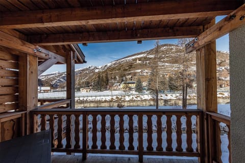 A covered wooden balcony with stunning views of the surrounding snow-capped mountains.