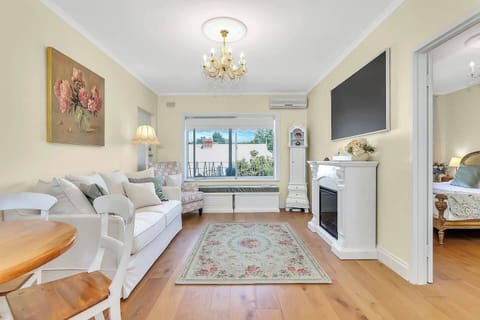 Rest in the living room, where a sparkling chandelier, two-seater sofa, armchair, and electric fireplace create a dreamy retreat.