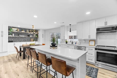 Discover a stylish, remodeled open-concept living room, kitchen, and dining area with new appliances, custom quartz countertops, and backsplash. Perfect for cooking, entertaining, and relaxing in a modern, functional space.