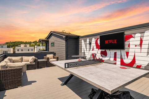 Rooftop: Spacious rooftop hangout area with comfortable lounge seating, a TV, and a ping pong table.