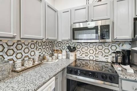 This stylish kitchen boasts a striking honeycomb backsplash that adds contemporary flair, while sleek gray cabinetry and polished granite countertops create a perfect space for your culinary adventures.