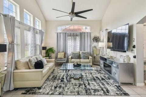 Enjoy the warm natural light pouring in through large windows in this stylish living room, complete with a sleek glass coffee table and a striking area rug. The contemporary seating beckons you to relax in this inviting space.