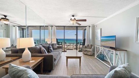 Spacious living room with plush seating, coastal charm, and stunning Gulf views through wall-to-wall glass doors. Relax with a movie or step onto the balcony to enjoy the ocean breeze.