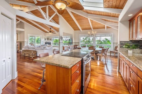 - Kitchen island connects seamlessly with dining and lounge   - Open floor plan with vaulted ceiling and tropical views   - Skylight and chandelier lighting brighten the gathering