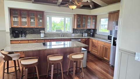 - Granite counters and wood cabinetry highlight full kitchen   - Bar stools at island offer space for casual breakfast bites   - Large windows frame tropical greenery while you cook here