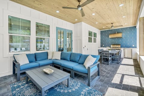 Screened in porch with built-in gas grill, sink, fridge, dining table, lounge seating, and a 4K Smart TV