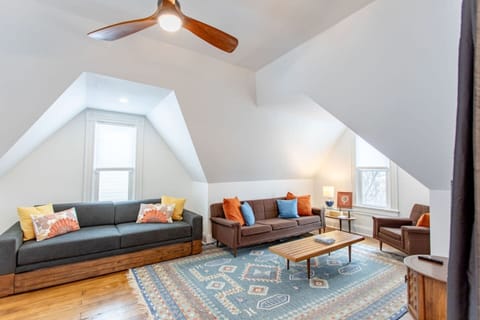 An upstairs living room that’s both cozy and spacious, featuring comfortable couches, a sitting chair, and large windows that fill the space with natural light, creating a relaxed and airy atmosphere.