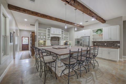 A spacious, open kitchen featuring rustic stone accents, a large island, and modern amenities for cooking and gathering.