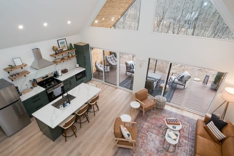 Bask in natural light and pond views from this stylish open-concept living area—featuring a fully equipped kitchen, cozy seating, and direct access to the outdoor deck.