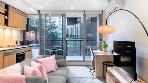 A smartly styled apartment lounge pairing a comfortable sofa with an integrated, sunlit desk corner.