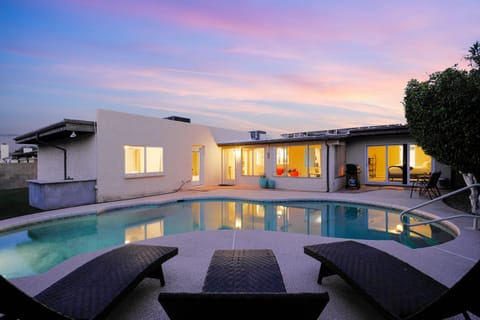 Inviting sparkling pool with relaxing lounge chairs, a BBQ for outdoor grilling, and a charming bistro table with seating for a perfect poolside experience.