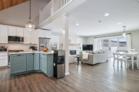 Welcome to this inviting lakeside escape! The open-concept layout seamlessly blends a chic kitchen with soft blue cabinets, stainless-steel appliances, and a cozy dining nook.