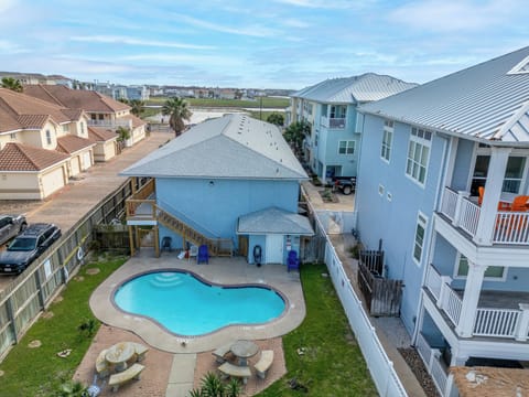 Aerial view of a charming pool surrounded by greenery and cozy lounge chairs. Cool off, relax, and soak up the sun in this peaceful, inviting oasis.
